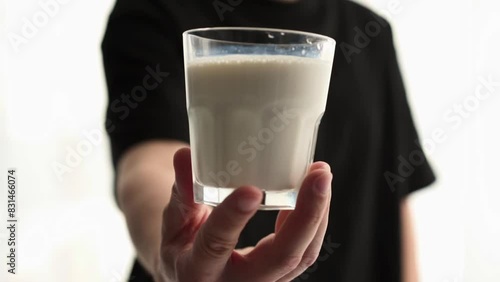 a man drinks milk from a transparent glass.
The guy drinks kefir and wipes his face photo