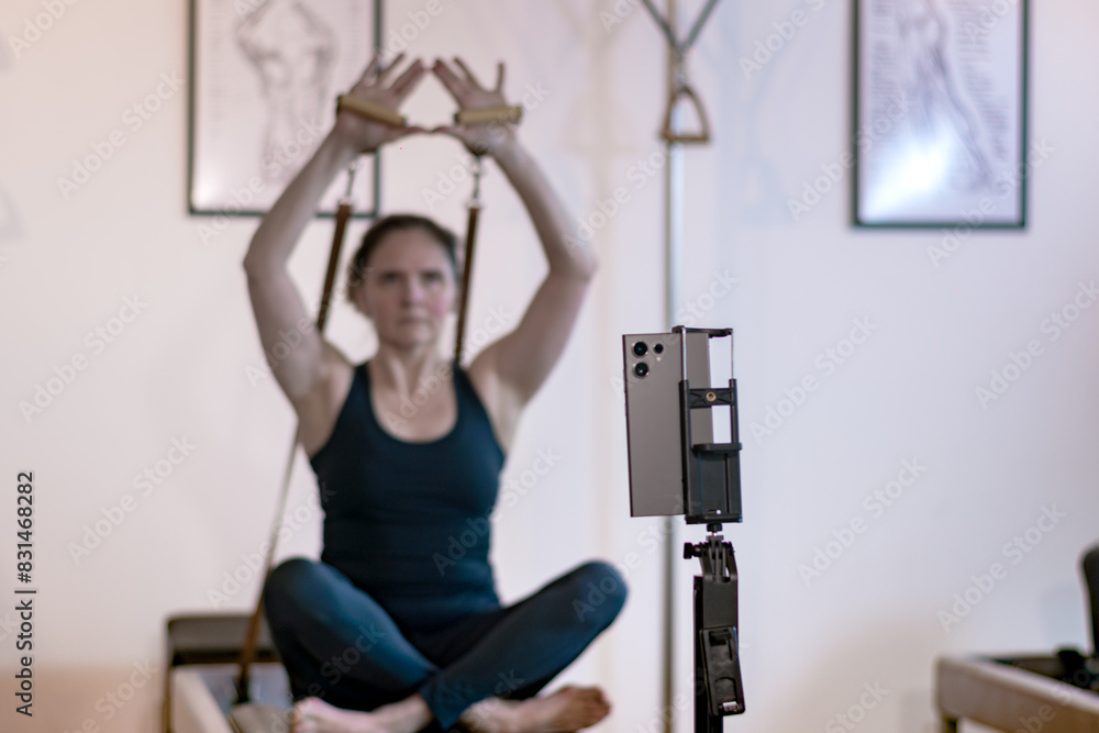Woman teaching pilates exercises from her cell phone. Woman teaching pilates exercises from her cell phone.