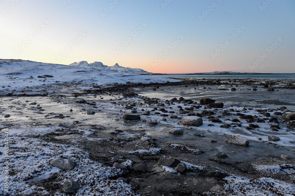 Wide angle shot of ice and boulders along the Norwegian coast, on a snowy winter morning.