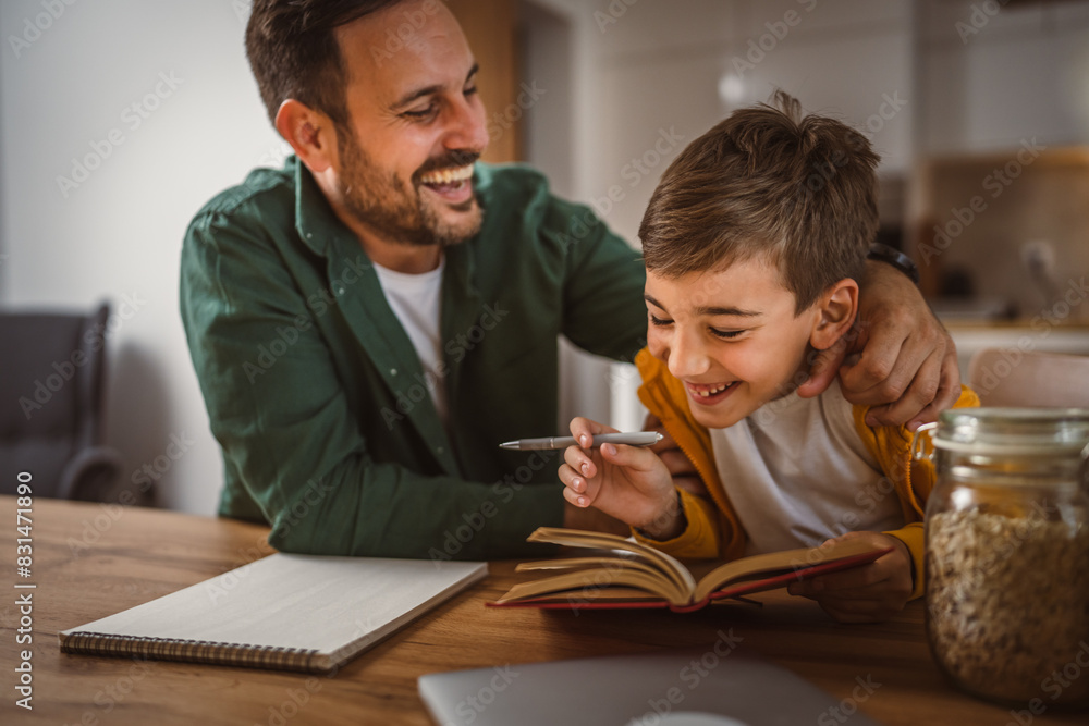 Son read a book and have fun while spend time with his father at home Son read a book and have fun while spend time with his father at home