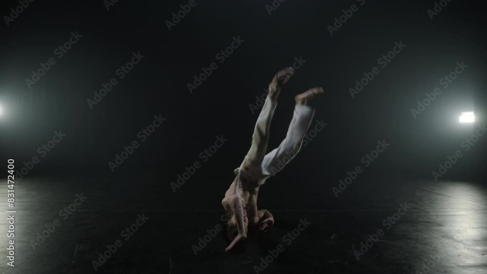 Group of a professional dancers are practicing capoeira in darkness against a spotlight on a black background of studio. Afro-Brazilian martial art that combine elements of dance. Group of a professional dancers are practicing capoeira in darkness against a spotlight on a black background of studio. Afro-Brazilian martial art that combine elements of dance.