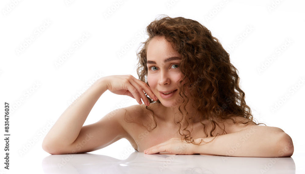 Obraz premium Portrait of tender young woman with no makeup perfect face, curly brown hair posing isolated on white background. Concept of natural beauty, skincare, wellness, cosmetology, cosmetics
