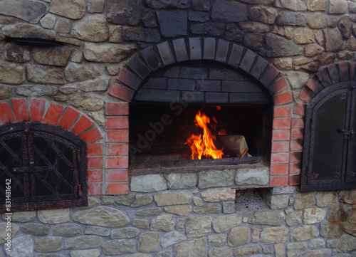 Fire burns in wood stove with soot on stones over fireplace