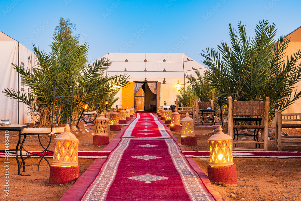 Luxury tent camp illuminated with fire lamps at Erg Chebbi Sahara desert at evening near Merzouga town, Morocco, North Africa