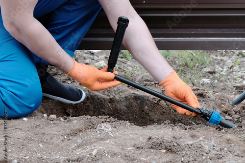 Plumber installs a sprinkler for automatic watering using a flexible connection, hands close-up