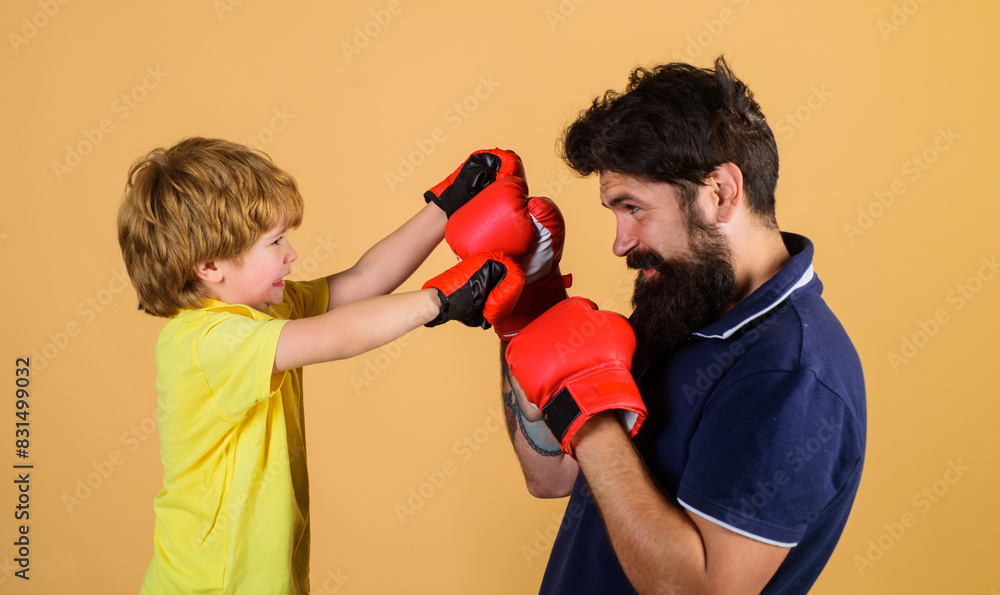 Kid boxer with coach at boxing training. Small son doing boxing exercise with father in gym. Child and coach in boxing ring. Boy and trainer in boxing gloves. Sport lifestyle, fitness. Family workout. Kid boxer with coach at boxing training. Small son doing boxing exercise with father in gym. Child and coach in boxing ring. Boy and trainer in boxing gloves. Sport lifestyle, fitness. Family workout.