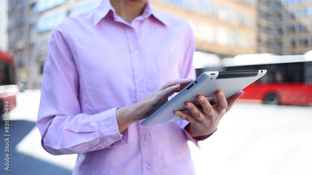 Young businesswoman standing on the street and using tablet