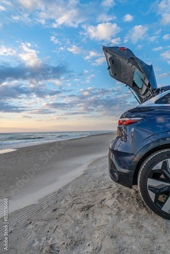 Car trunk open against a background of sunset over the beach