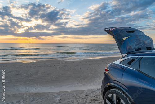 Car trunk open against a background of sunset over the beach