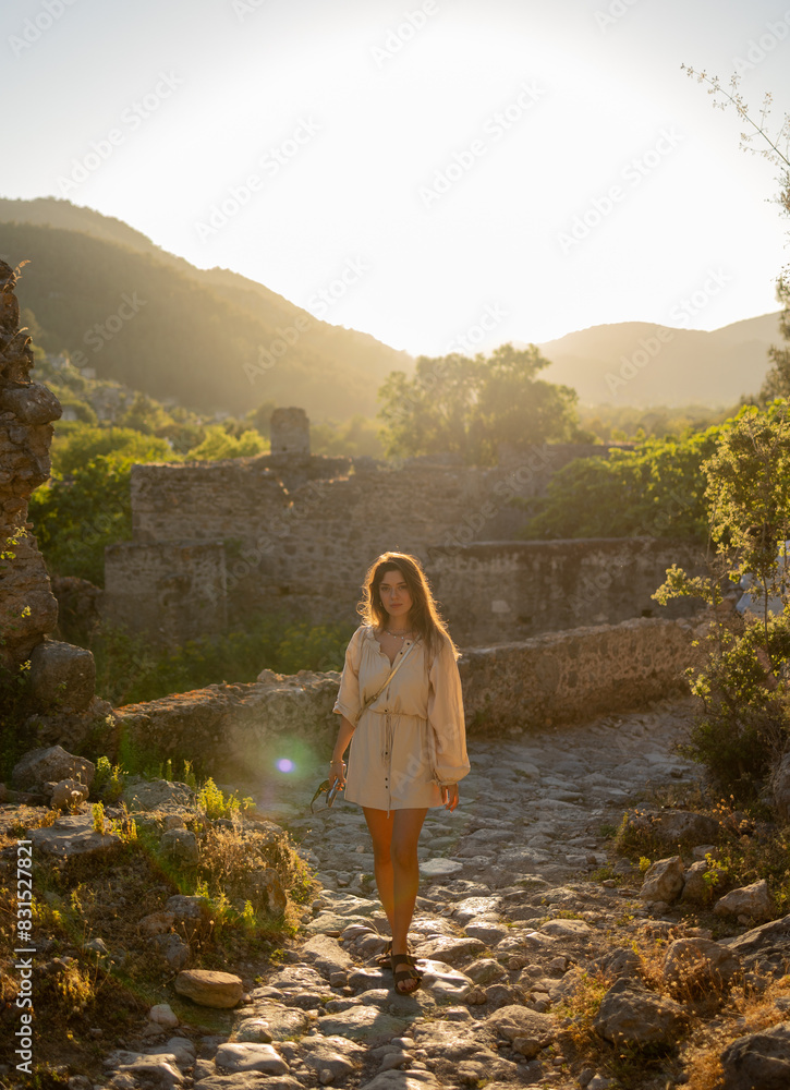 Naklejka premium A young tourist girl walking around Kayakoy, Fethiye. It is an abondoned village and it is located in Muğla which is south west of Turkey. She is in vacation. Freedom, travel, tourism concept photo.