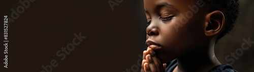 A child dressed in colorful traditional attire, stands with hands clasped in a gesture of prayer against a vibrant background