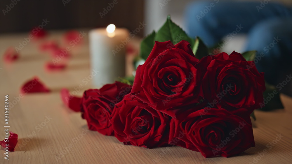 Beautiful roses bouquet lying on table near burning candle close up. Red flowers Beautiful roses bouquet lying on table near burning candle close up. Red flowers