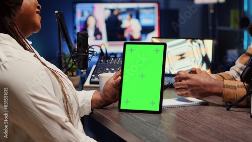 Green screen tablet hold by woman on podcast discussing with guest during marathon stream for humanitarian cause. Chroma key device used by host to check gathered donations from audience during show photo