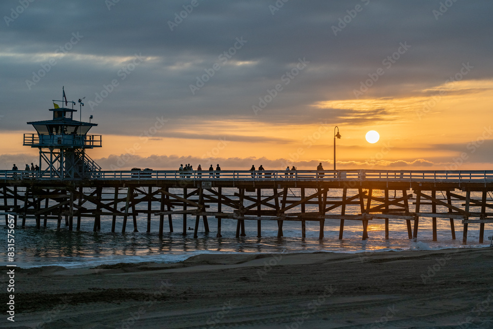 A beautiful golden beach sunset on a summer evening with people enjoying the scenery A beautiful golden beach sunset on a summer evening with people enjoying the scenery
