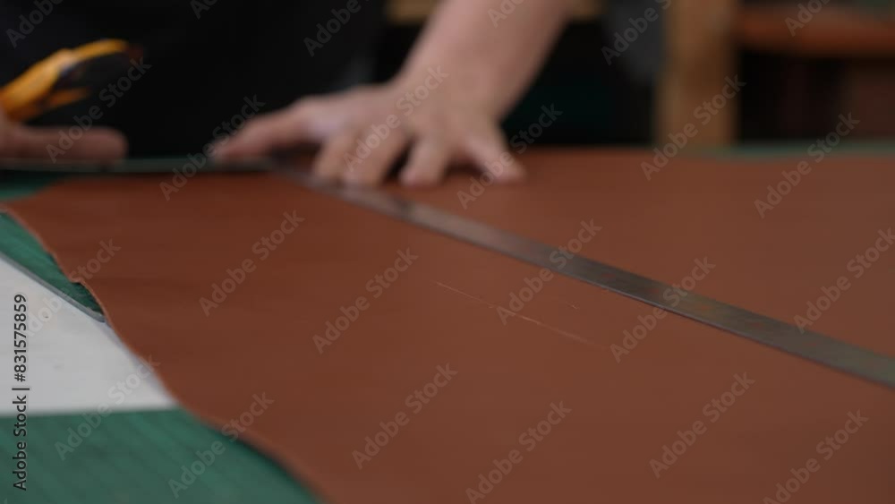 Leatherworker measuring and cutting leather in workshop. Leatherworker measuring and cutting leather in workshop.