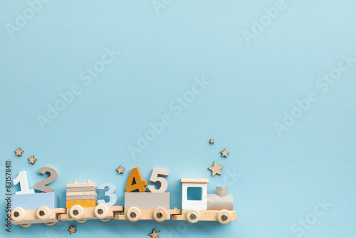 Educational wooden toy train with numbers on light blue background. Ideal for concepts related to early childhood education  cognitive development in children. Flat lay  top view.