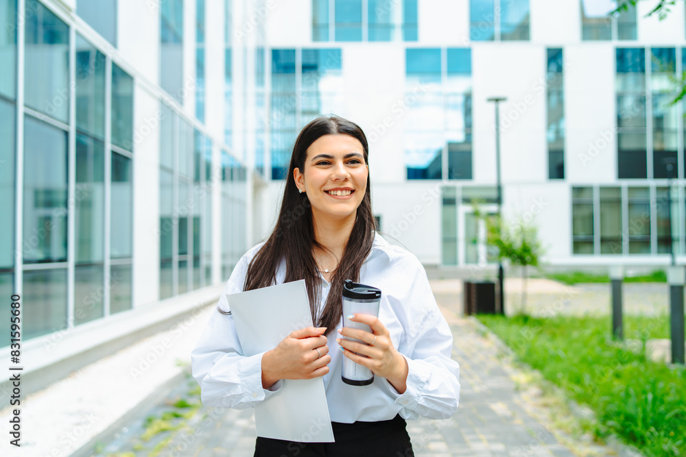 One young successful business woman going to work at business office modern building while holding coffee and papers One young successful business woman going to work at business office modern building while holding coffee and papers