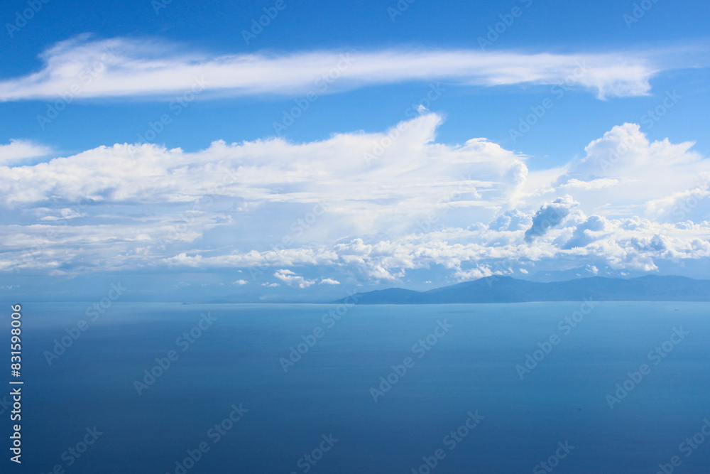 A serene seascape with a clear blue sky and scattered clouds above an island in the distance. koh samui, Thailand A serene seascape with a clear blue sky and scattered clouds above an island in the distance. koh samui, Thailand
