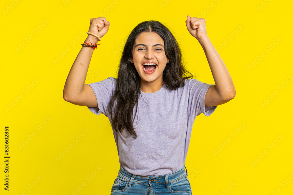 Happy joyful Indian woman celebrating success victory, winning birthday, lottery jackpot goal achievement play game good positive news, triumph. Young Arabian girl isolated on yellow studio background Happy joyful Indian woman celebrating success victory, winning birthday, lottery jackpot goal achievement play game good positive news, triumph. Young Arabian girl isolated on yellow studio background