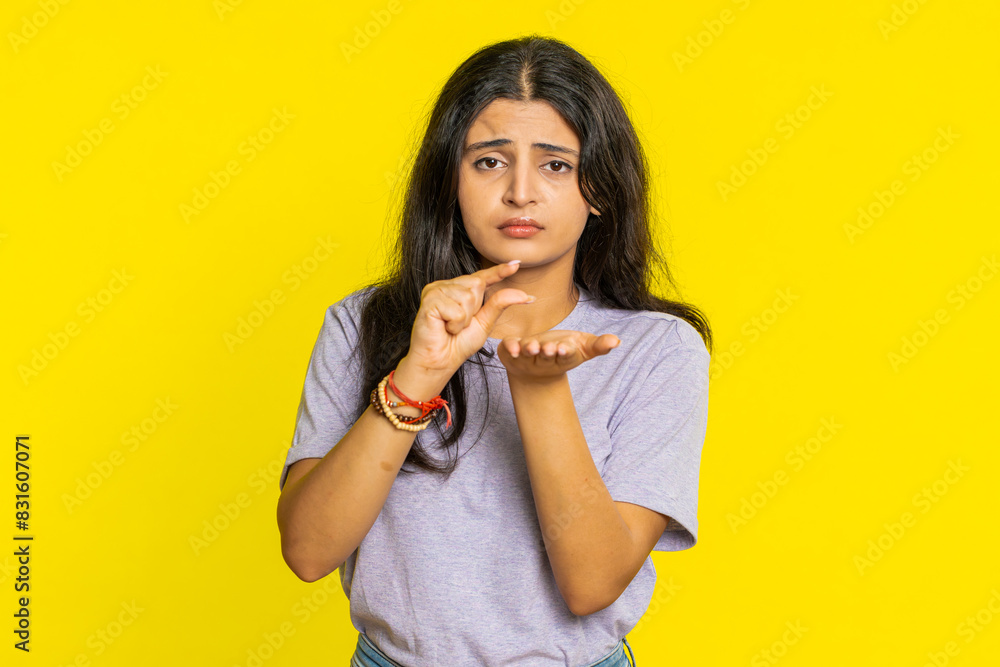 Need some more, please give me. Indian woman showing a little bit gesture with sceptic smile showing minimum sign, measuring small size, begging help. Arabian girl isolated on yellow studio background Need some more, please give me. Indian woman showing a little bit gesture with sceptic smile showing minimum sign, measuring small size, begging help. Arabian girl isolated on yellow studio background