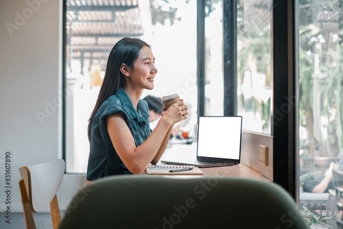 A woman is sitting at a desk with a laptop and a cup of coffee. She is smiling and she is enjoying her coffee and work Free Download A woman is sitting at a desk with a laptop and a cup of coffee. She is smiling and she is enjoying her coffee and work - GFXLoad