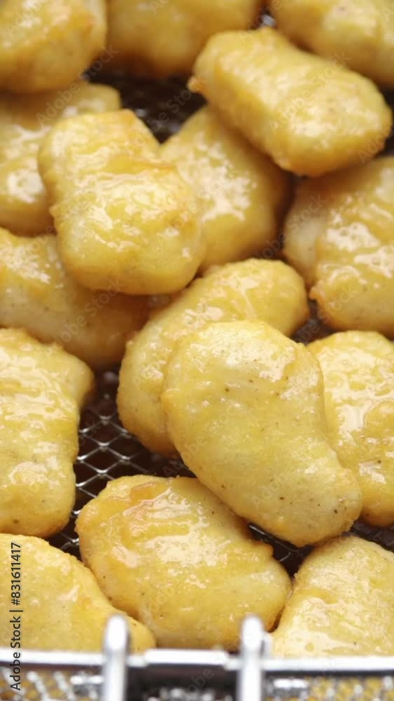 Deep fry chicken nuggets in deep fryer basket and lift them out of the boiling oil. Close-up shot Deep fry chicken nuggets in deep fryer basket and lift them out of the boiling oil. Close-up shot