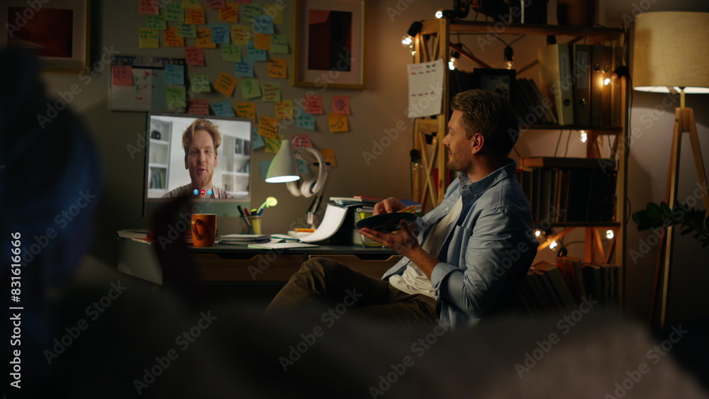 Friends enjoying video chat in cozy evening. Cheerful guys talking by web cam Friends enjoying video chat in cozy evening. Cheerful guys talking by web cam