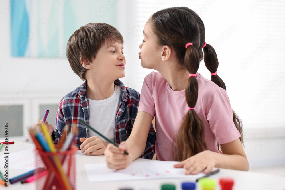 Happy brother and sister drawing at white table in room Happy brother and sister drawing at white table in room