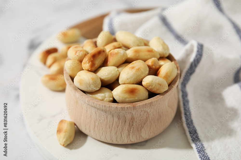 Roasted peanuts in bowl on white table, closeup Roasted peanuts in bowl on white table, closeup