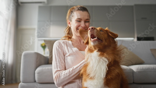 Woman hugging adorable dog with happy smile at home close up. Girl caressing pet © stockbusters