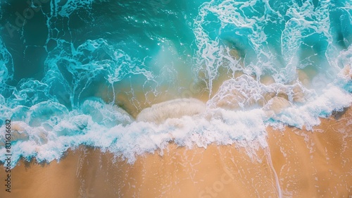 Aerial view of turquoise ocean wave crashing onto sandy shore with white foam