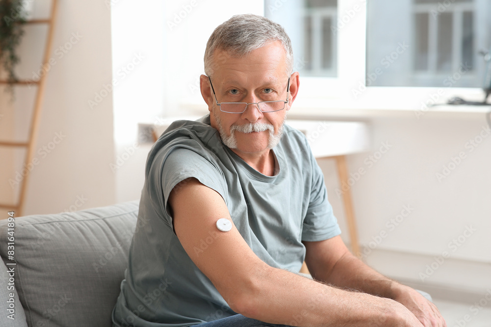 Senior man with glucose sensor for measuring blood sugar level at home. Diabetes concept Senior man with glucose sensor for measuring blood sugar level at home. Diabetes concept