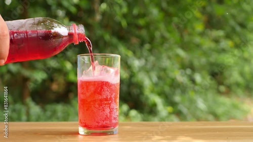 Pour colorful soft drinks into glass bottles and place them on the table.