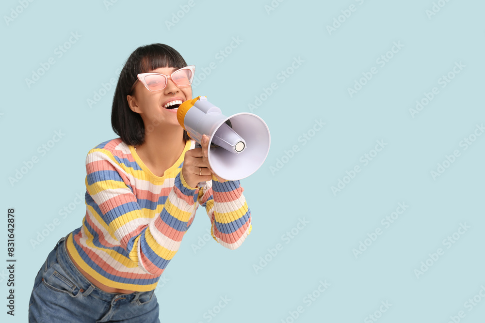 Young woman with megaphone on blue background Young woman with megaphone on blue background