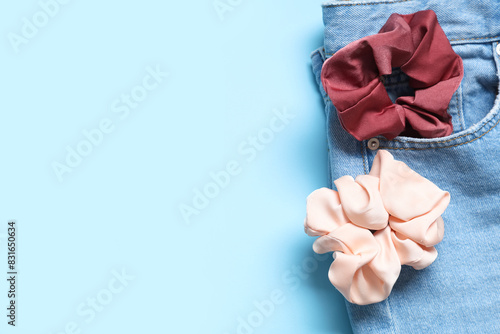 Jeans with trendy silk scrunchies on blue background photo