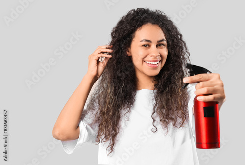 Εκτύπωση καμβά Beautiful young happy African-American woman with hair spray on grey background