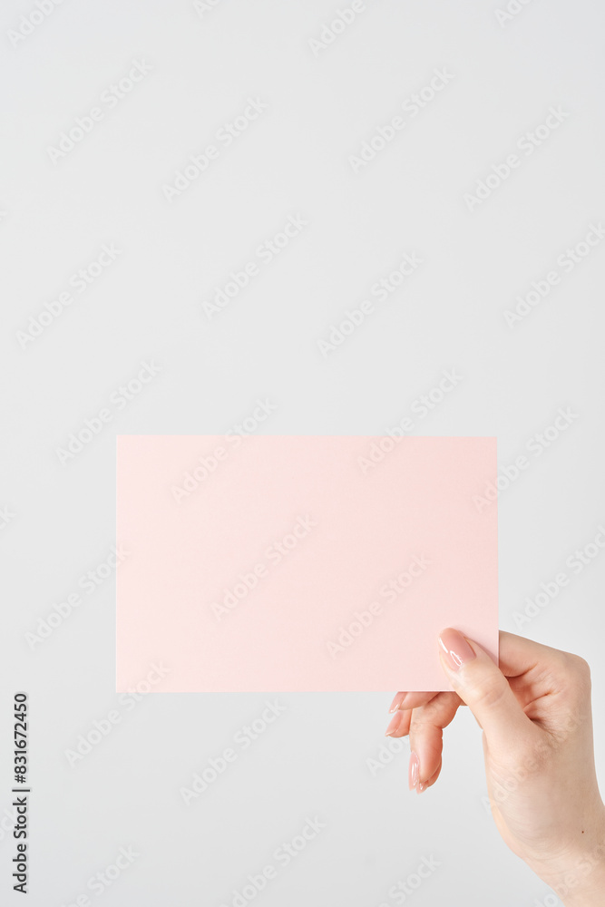 Fototapeta premium ピンク色の紙を持つ女性の手元