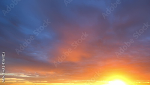 A stunning sunrise with brilliant hues of orange and yellow radiating from the horizon  blending into deep shades of blue and purple in the sky. The scene is serene and beautiful. Cloud background. 