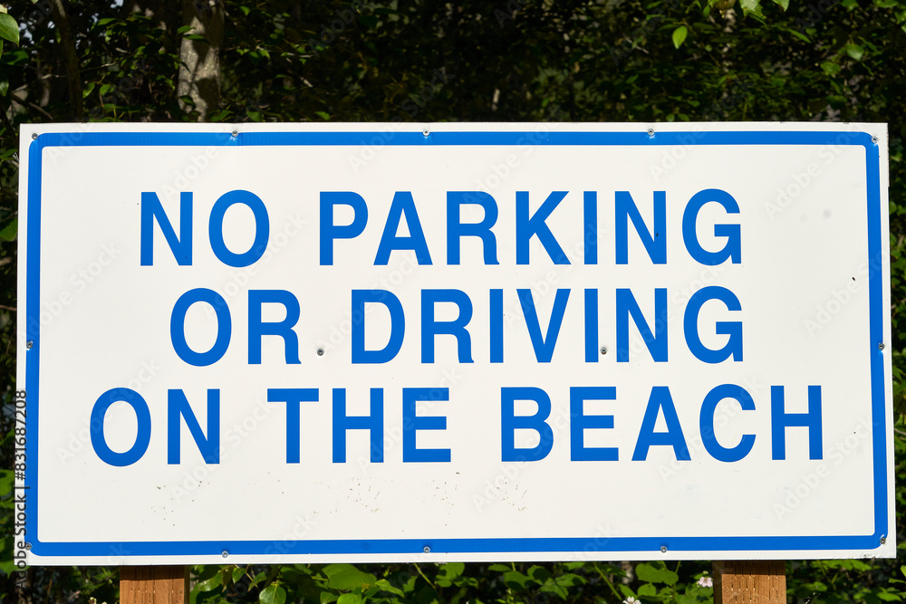 Large blue and white sign that states no parking or driving on the beach. Large blue and white sign that states no parking or driving on the beach.