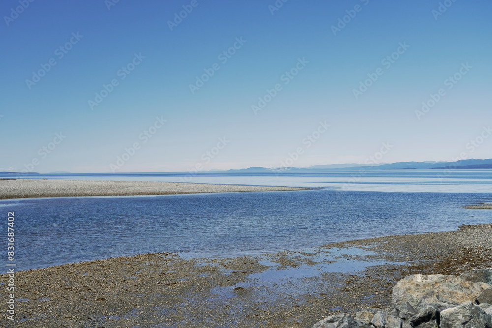 Minimalist view, the distant sky and islands, the ocean with a sandbar and a rocky beach. Minimalist view, the distant sky and islands, the ocean with a sandbar and a rocky beach.