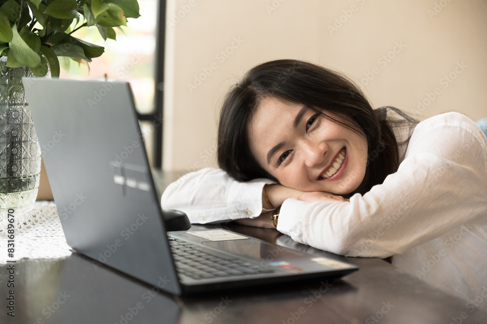 Asian woman sitting on chair at cozy office workplace and fallen asleep while she works on a laptop, remote work, E learning concept.Business woman hard worked and fell asleep on the the table. Asian woman sitting on chair at cozy office workplace and fallen asleep while she works on a laptop, remote work, E learning concept.Business woman hard worked and fell asleep on the the table.