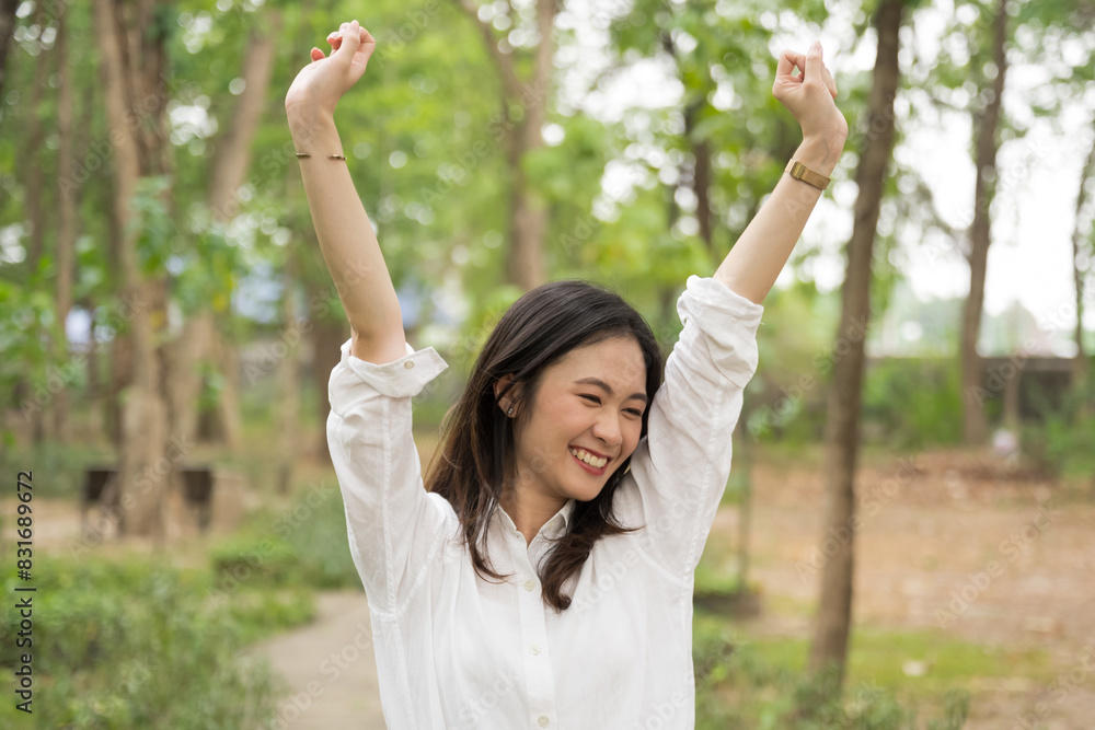 Portrait of asian woman breathing fresh air in a forest.Carefree asian girl smiling and enjoying summer sunny day in park.Young woman arms raised enjoying the fresh air in green park. Portrait of asian woman breathing fresh air in a forest.Carefree asian girl smiling and enjoying summer sunny day in park.Young woman arms raised enjoying the fresh air in green park.