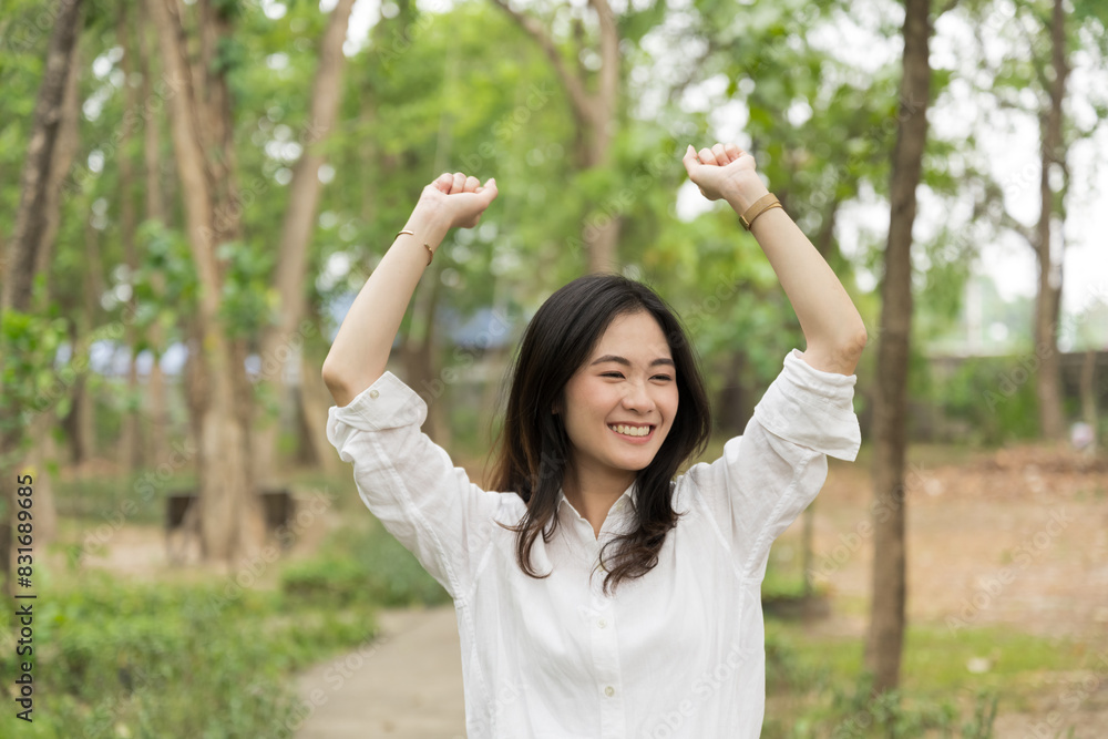 Portrait of asian woman breathing fresh air in a forest.Carefree asian girl smiling and enjoying summer sunny day in park.Young woman arms raised enjoying the fresh air in green park. Portrait of asian woman breathing fresh air in a forest.Carefree asian girl smiling and enjoying summer sunny day in park.Young woman arms raised enjoying the fresh air in green park.
