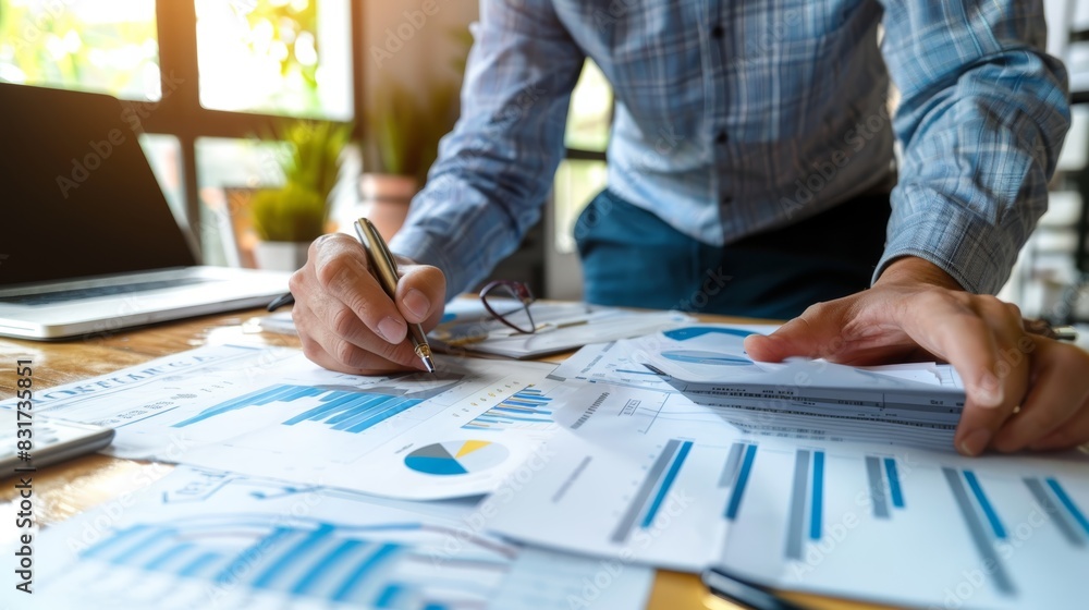 Business professional analyzing financial documents and data in a workspace with charts and graphs. High-quality image for corporate use. Business professional analyzing financial documents and data in a workspace with charts and graphs. High-quality image for corporate use.