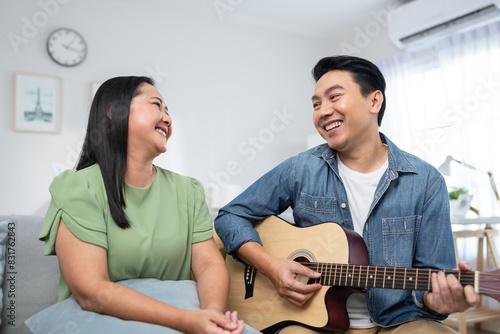 Asian couple spending free leisure time together in living room in house. 