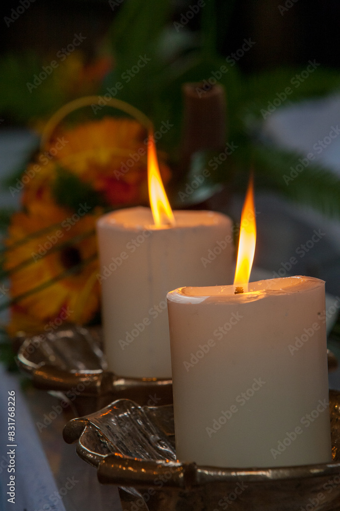 Lit candles create a cozy ambiance with a decorative flower in the background, casting a soft golden light Lit candles create a cozy ambiance with a decorative flower in the background, casting a soft golden light