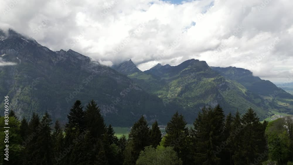 The scenic view of Glarus, Switzerland, as mountain peaks oversee a valley dotted with a charming residential area, epitomizes the harmony between nature and habitation. The scenic view of Glarus, Switzerland, as mountain peaks oversee a valley dotted with a charming residential area, epitomizes the harmony between nature and habitation.