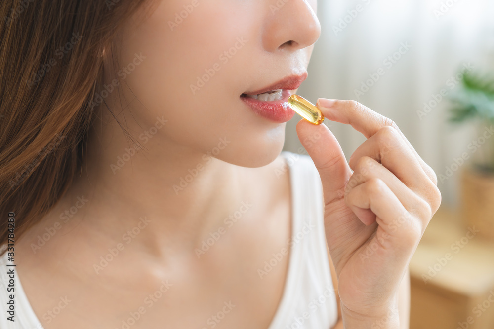 Dietary supplement, pretty asian young woman, girl hand holding medical pill capsule, take or eat vitamin fish oil for treatment for skin, hair and nail strengthener near window at home, healthcare. Dietary supplement, pretty asian young woman, girl hand holding medical pill capsule, take or eat vitamin fish oil for treatment for skin, hair and nail strengthener near window at home, healthcare.