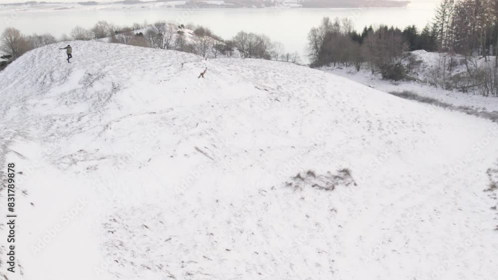 Man Run Uphill on Snowy Hill with Shovel Sledge - Aerial Drone Static Shot Man Run Uphill on Snowy Hill with Shovel Sledge - Aerial Drone Static Shot