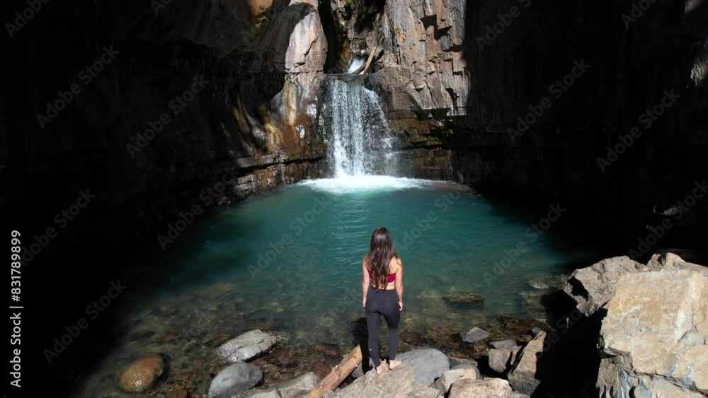 Aerial View of Woman Walking on Rocks in Canyon in Front of Small Waterfall on Sunny Summer Day Aerial View of Woman Walking on Rocks in Canyon in Front of Small Waterfall on Sunny Summer Day
